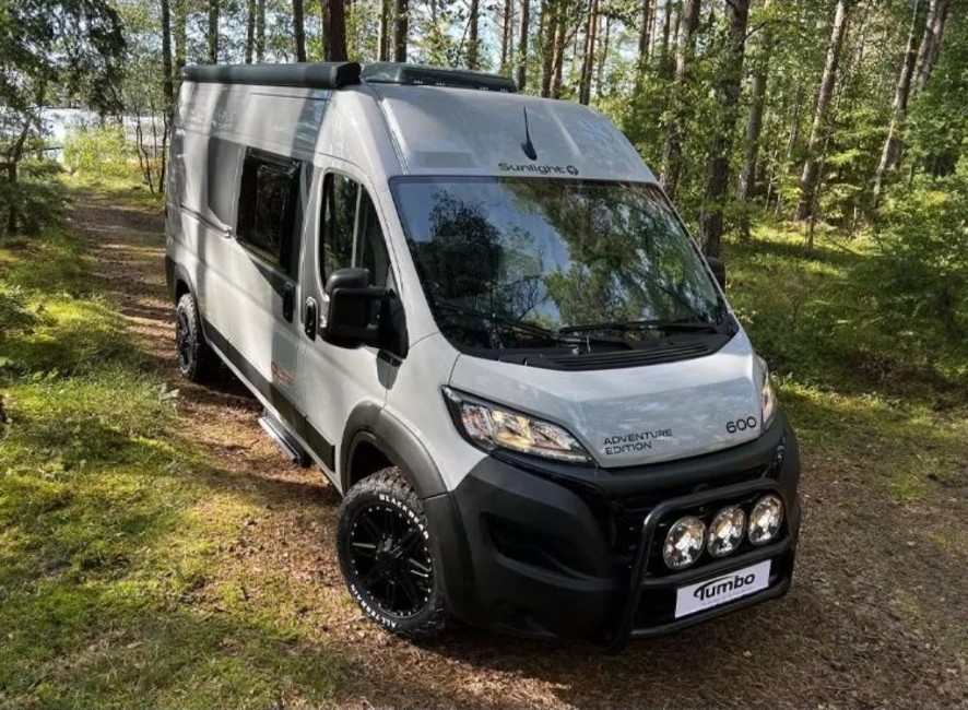 Silver Fiat Ducato overlander with steel bull bar, triple spot lights, extended wheel arches and all-terrain tyres in woodland